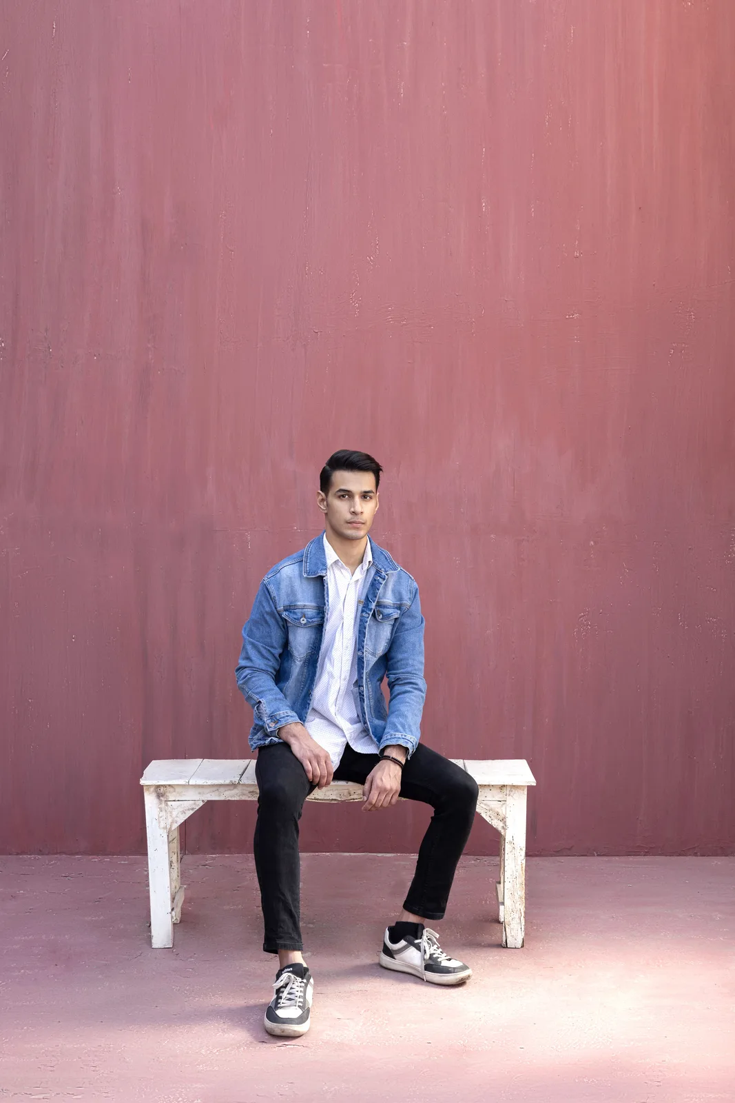 Sagar Shabbir seated on bench in denim jacket