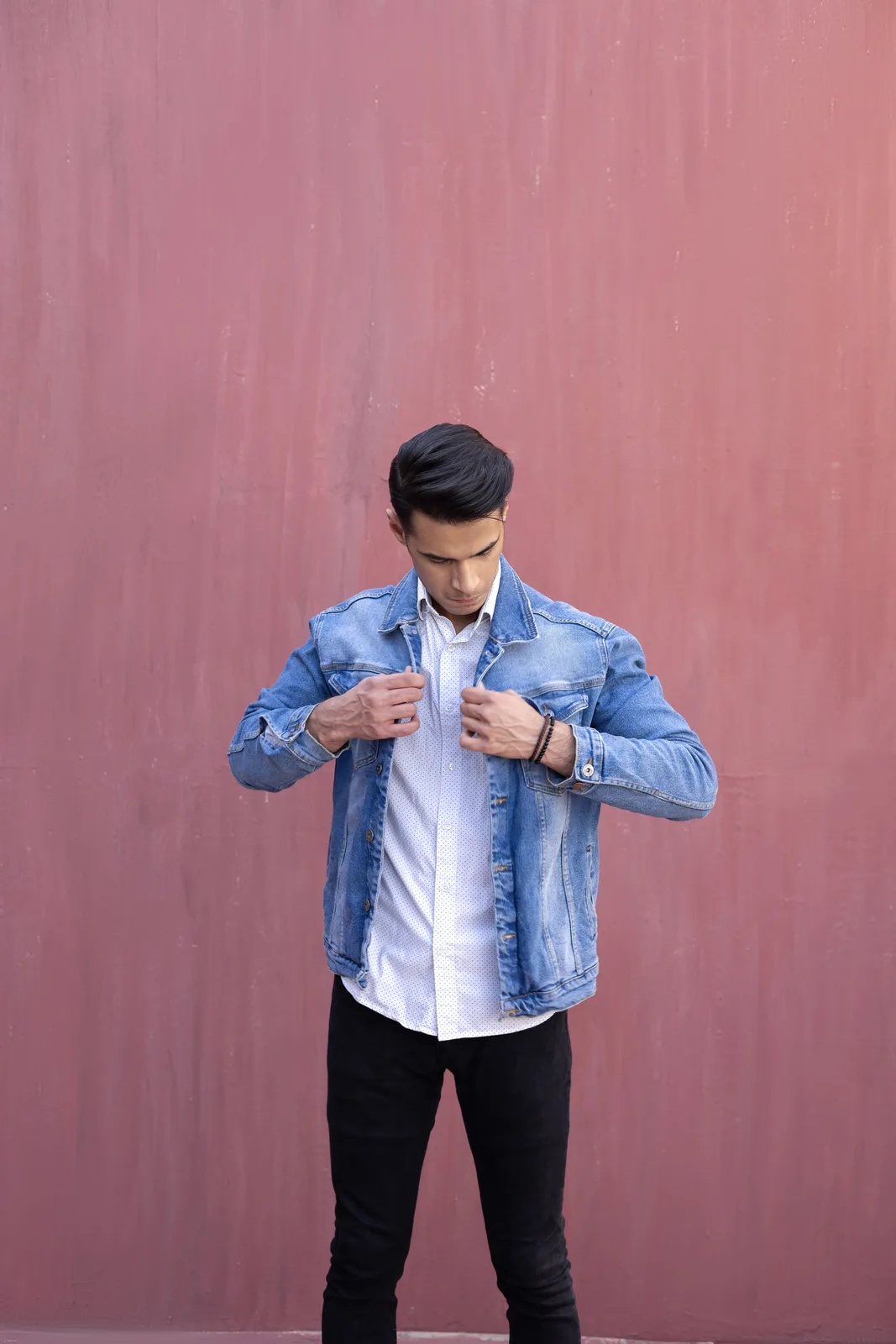 Sagar Shabbir adjusting denim jacket, looking down