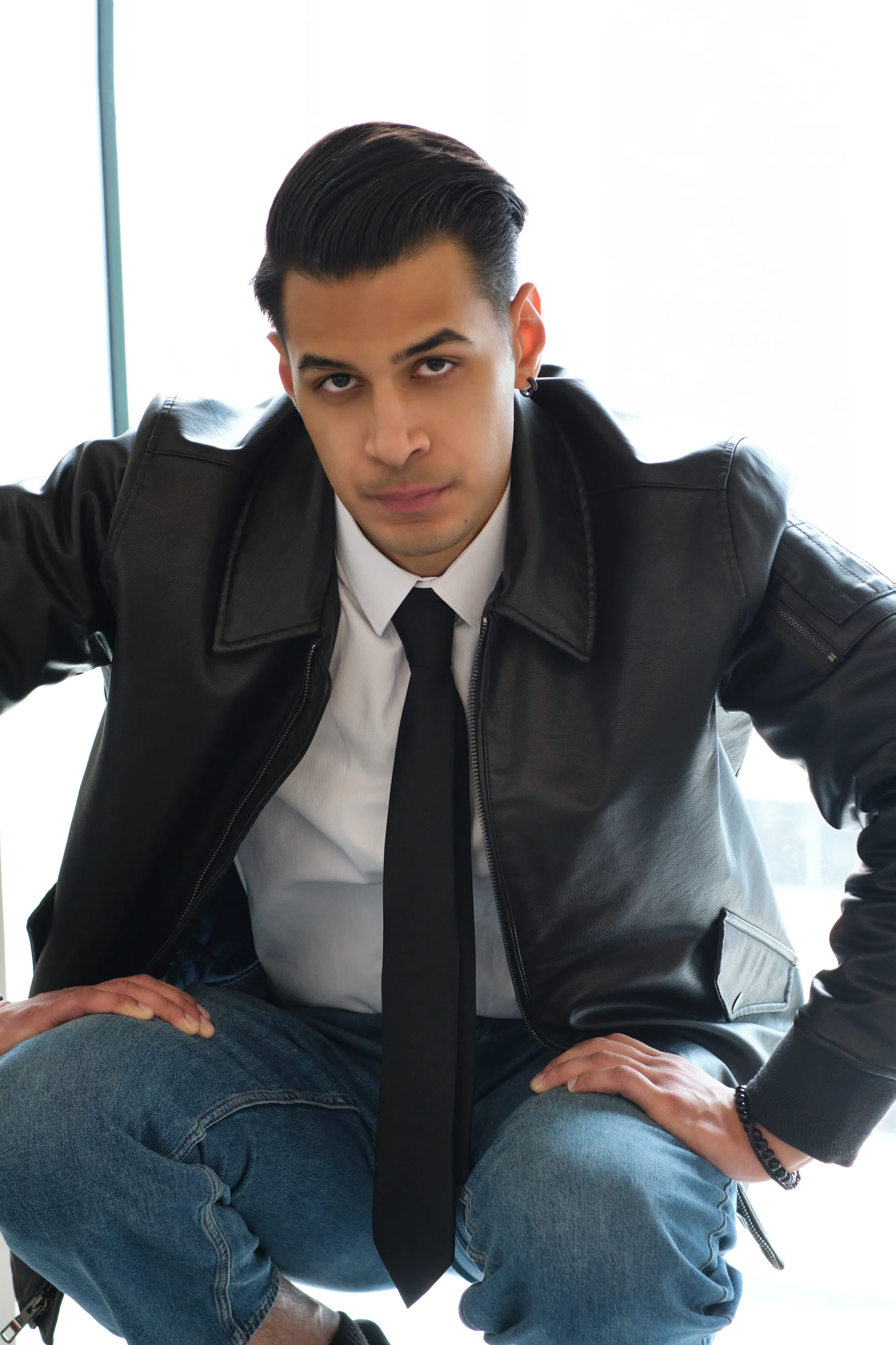 Sagar Shabbir — leather jacket and tie, seated editorial