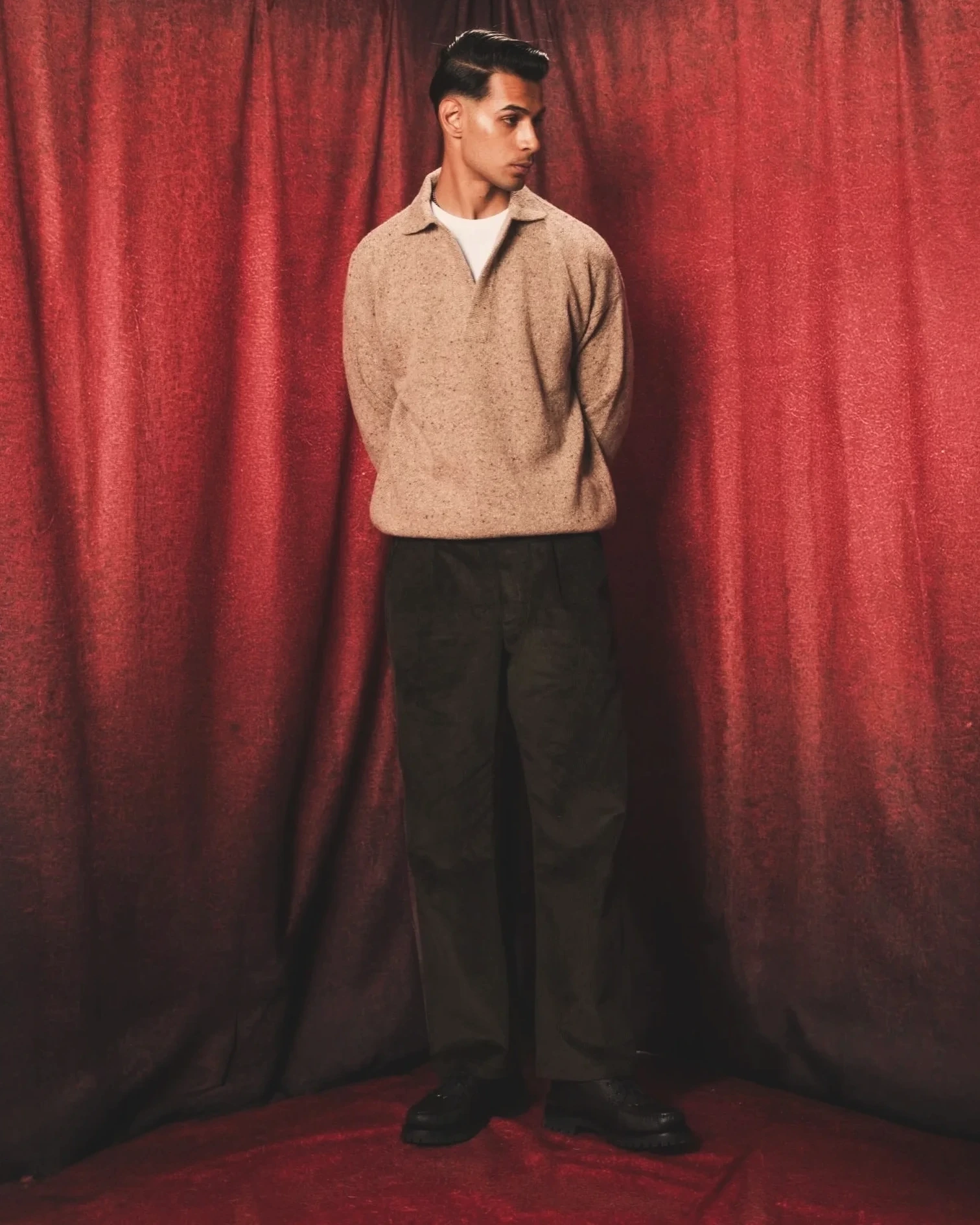 Sagar Shabbir — beige knit polo and corduroy trousers, red curtain studio